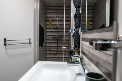 Gros plan sur la vasque moderne de la salle d'eau privée de la Chambre d'hôtes Ainhoa, miroir, rangement tricoté original et douche à l'italienne à Espelette.