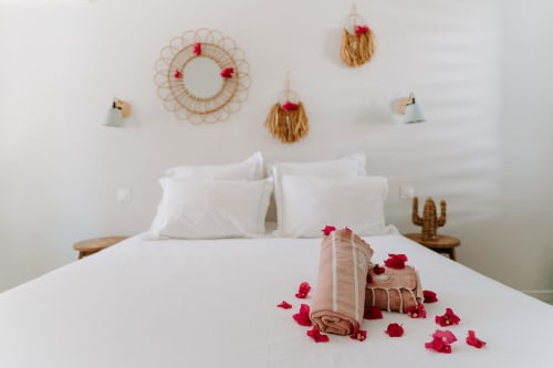 Chambre romantique à Habitation L'SEO : lit blanc, pétales de fleurs rouges, décor mural tissé et touches tropicales à Sainte-Anne