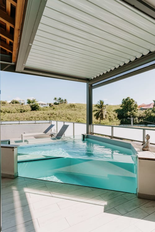 Terrasse de piscine couverte moderne à l'Habitation l'SEO à Sainte-Anne avec eau turquoise, chaises longues et vues sur les collines