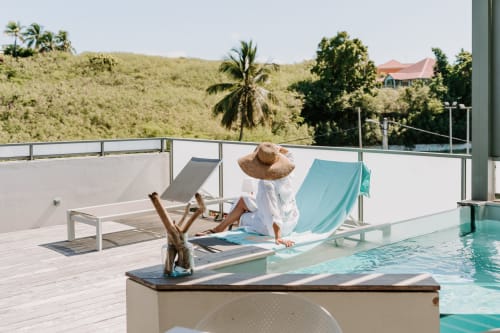Femme détente au bord de la piscine de l'Habitation l'SEO à Sainte-Anne, Guadeloupe, vue sur les collines tropicales