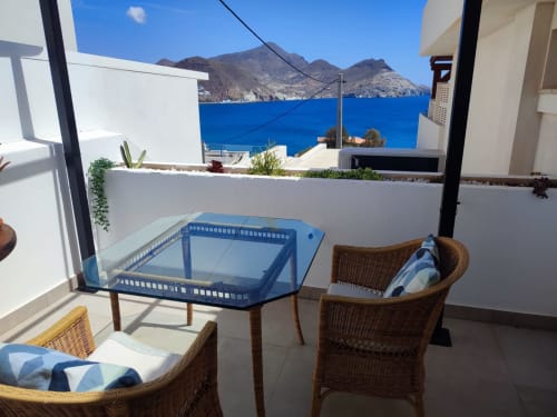Zona de estar en balcón con vistas al mar azul y las montañas de El Faro de Los Genoveses, Almería