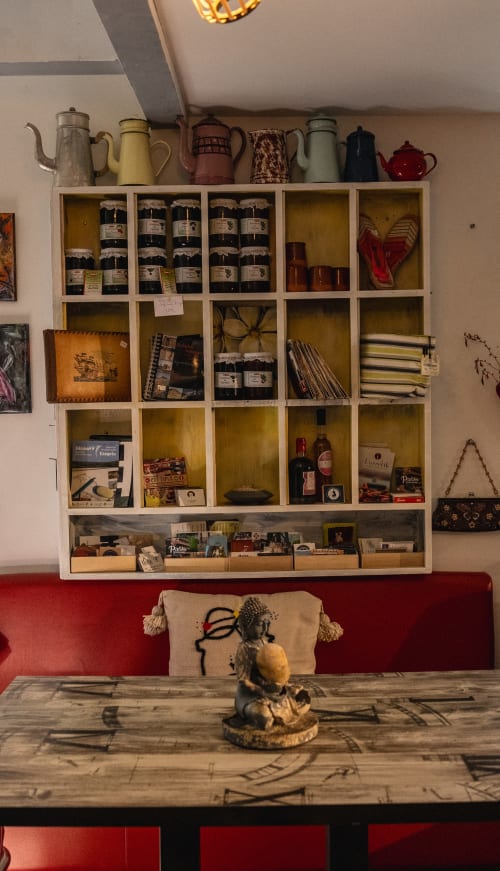 Coin gourmand du moulin : étagères de confitures artisanales, cafetières vintage et banquette rouge pour un moment de partage au Pays Basque.