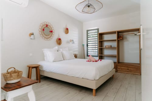 Chambre moderne et lumineuse à l'Habitation l'SEO à Sainte-Anne avec draps blancs, touches de bois et art mural décoratif.