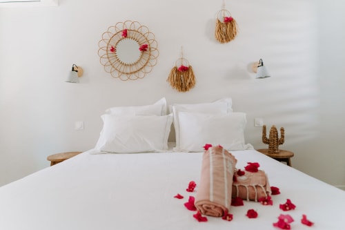 Chambre romantique à l'Habitation I'SEO à Sainte-Anne avec pétales de roses, décoration murale tissée et literie blanche à Le Malanga