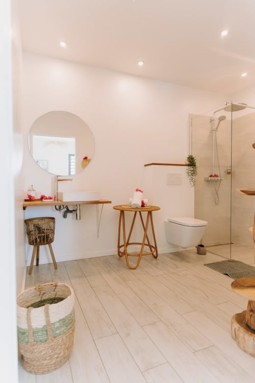 Salle de bain moderne à l'Habitation l'SEO à Sainte-Anne avec miroir rond, meuble vasque en bois, douche à l'italienne et décoration naturelle