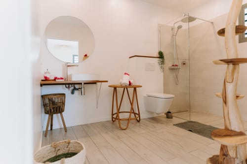 Salle de bain moderne à l'Habitation I'SEO avec douche ouverte, vasque en bois, miroir rond et décoration naturelle