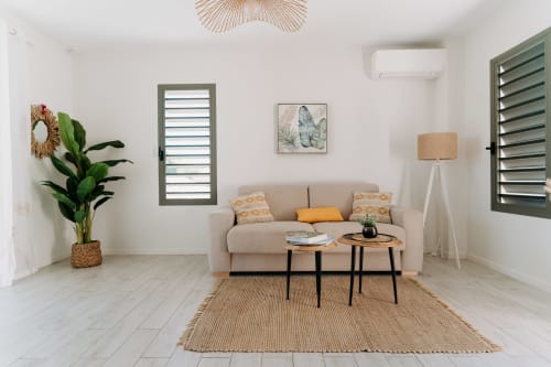 Salon moderne à l'Habitation I'SEO à Sainte-Anne avec canapé beige, plante en pot, tables en bois et œuvres d'art tropical