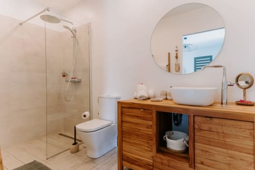 Salle de bain moderne à l'Habitation I'SEO avec douche vitrée, meuble vasque en bois, miroir rond et lavabo blanc