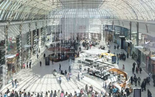 Modern covered marketplace at Disneyland resort in Serris with glass ceiling, shops, and crowds of visitors