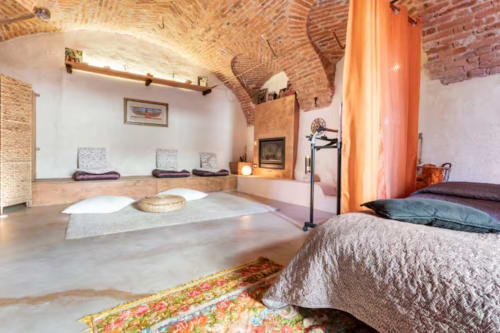 Rustic brick vaulted yoga studio at CasaRosada B&B in Vidracco with meditation mats and fireplace