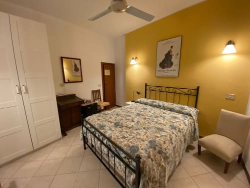 Camera da letto gialla luminosa ad Alloggio Le Casette a Verona con letto matrimoniale, testata in ferro battuto e comfort moderni