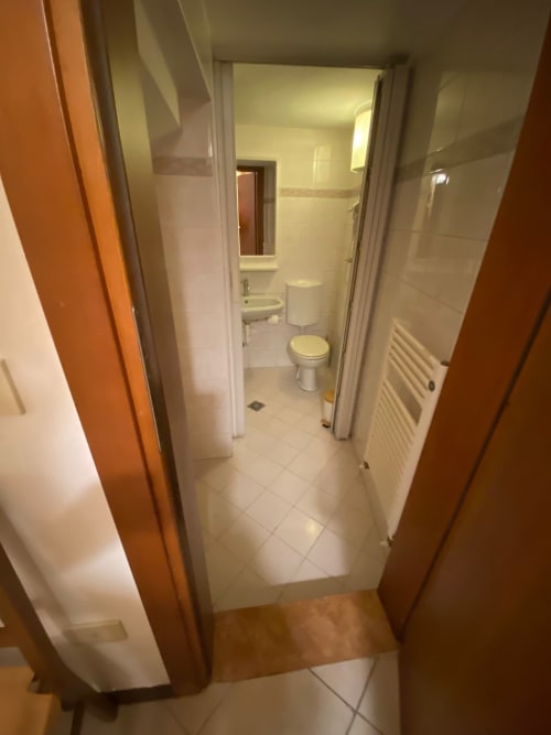 Ingresso del bagno di Alloggio Le Casette Verona con toilette, lavabo, doccia e pavimentazione in piastrelle bianche