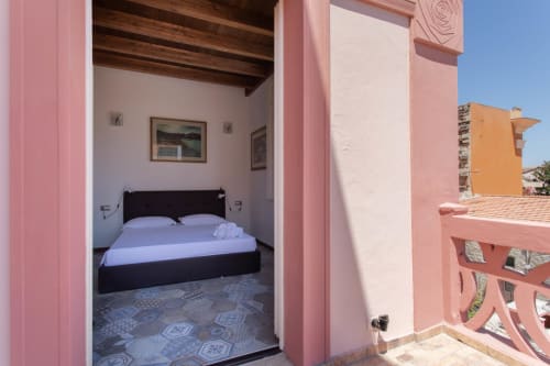 Camera da letto rosa con letto nero e pavimento in piastrelle decorate presso Maison Belle Époque a Oristano, Italia