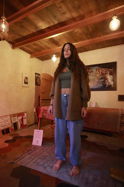 Woman standing in rustic room at CasaRosada B&B Vidracco with wooden beams and vintage furnishings
