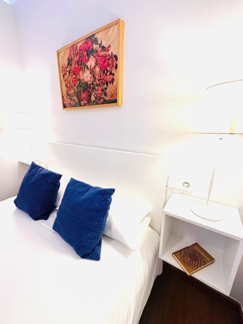 Dormitorio luminoso en Mérida con obras de arte floral, cojines decorativos azules y muebles blancos