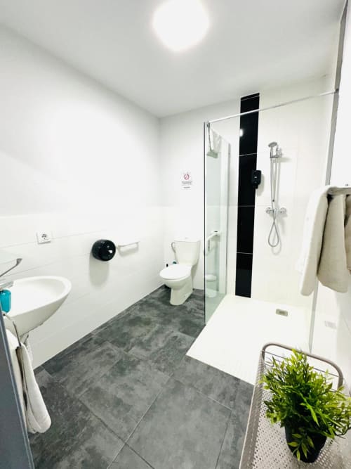 Baño moderno con ducha, inodoro, lavabo, pisos de azulejos grises y paredes blancas en el apartamento Gestyp-AT en Mérida