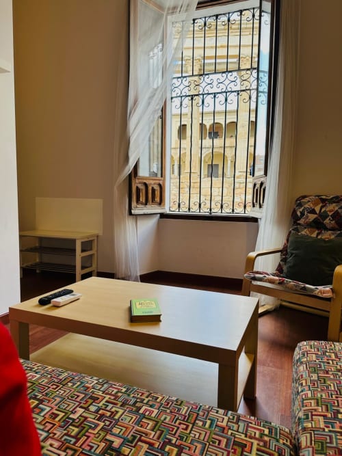 Acogedora sala de estar en Mérida con vista desde ventana, muebles de madera, alfombra geométrica colorida y decoración moderna