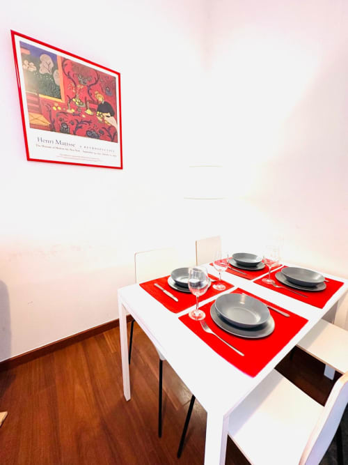 Comedor moderno en apartamento Gestyp-AT en Mérida con salvamanteles rojos y obra de Matisse en la pared