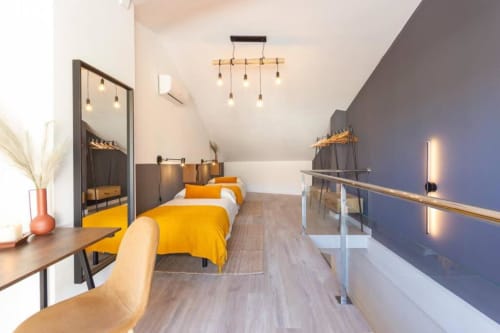 Habitación moderna con camas gemelas en J&A Apartments en Terrassa, ropa de cama amarilla, detalles de madera e iluminación contemporánea.
