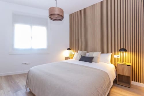 Dormitorio moderno en J&A Apartments de Terrassa con cama queen, pared de acento de madera, lámpara colgante y ventana luminosa