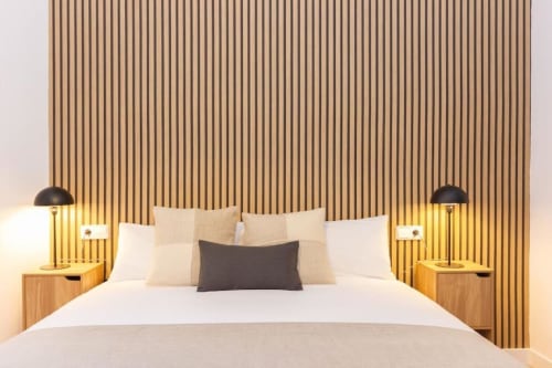 Habitación moderna en J&A Apartments Terrassa con pared revestida de madera, cama queen y iluminación ambiental