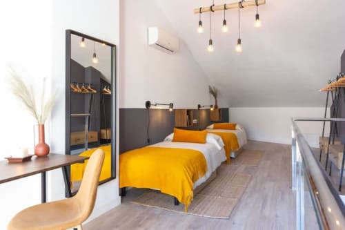 Dormitorio moderno en los Apartamentos J&A de Terrassa con camas individuales, ropa de cama amarilla y muebles contemporáneos