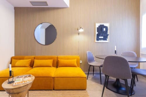 Salón moderno en J&A Apartments Terrassa con sofá amarillo, pared de madera y comedor contemporáneo