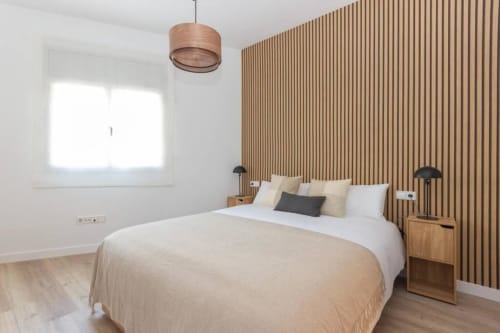 Dormitorio moderno en J&A Apartments en Terrassa con pared de acento de madera, luz colgante y ropa de cama natural