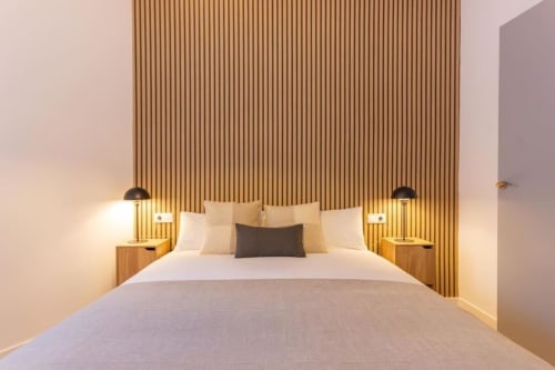 Dormitorio moderno en J&A Apartments Terrassa con cama queen, cabecero de madera, luces colgantes y decoración neutral
