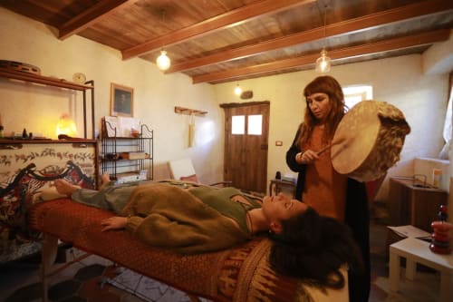 Wellness practitioner performs sound healing with frame drum on guest at CasaRosada B&B in Vidracco, Italy