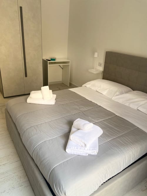 Camera moderna a La Maison a Bari con due letti, asciugamani bianchi, scrivania e vista sulla città