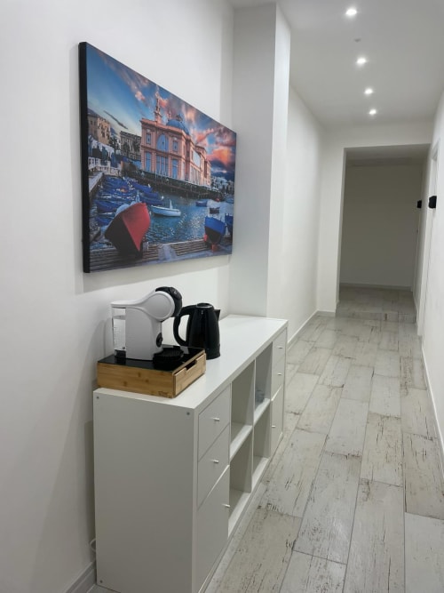 Corridoio moderno di hotel a Bari con TV a parete che mostra una scena costiera mediterranea e mobile bianco contenitore