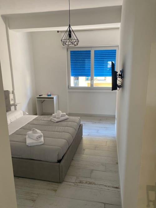 Camera moderna di La Maison Srls a Bari con letto, scrivania, persiane blu e lampada a sospensione geometrica