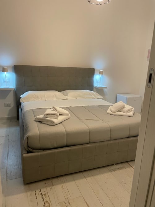 Camera moderna di La Maison a Bari con letto imbottito verde, biancheria bianca e asciugamani