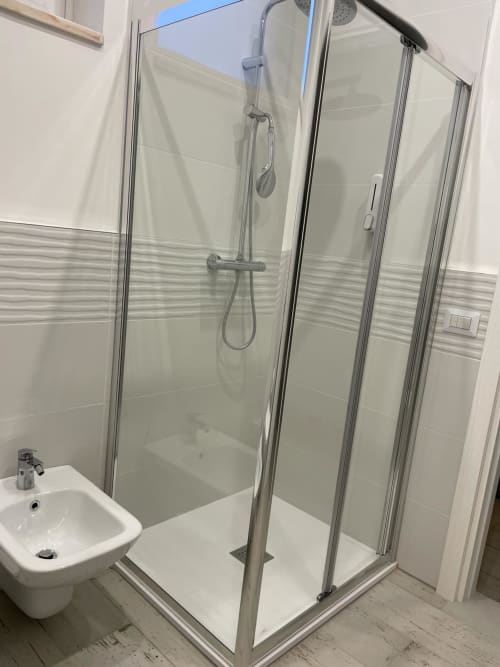 Moderna cabina doccia in vetro nella suite dell'hotel La Maison a Bari con soffione pioggia e lavabo bianco