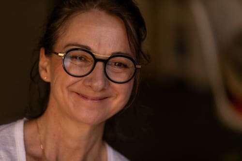 Woman with glasses smiling at Le Prieuré Notre-Dame bed and breakfast in Montfrin, France