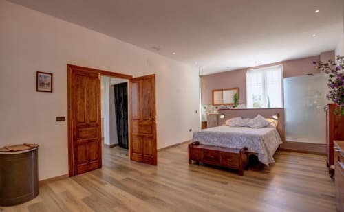 Spacious double bedroom with wooden furnishings, terrace view, and garden outlook at Finca Almenara De Copau, Zaragoza