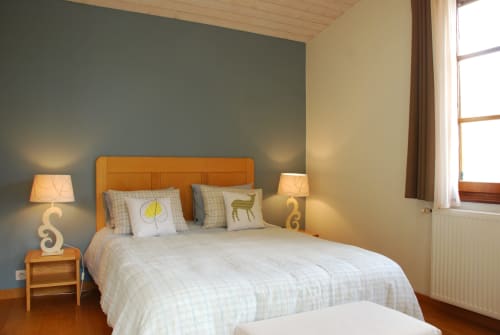 Chambre lumineuse à Entre Terre Et Ciel B&B à Rémuzat avec tête de lit orange, deux lampes de chevet et mur d'accent bleu-gris