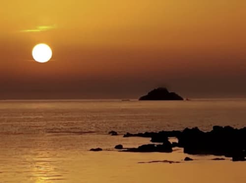 Coucher de soleil doré sur la mer Méditerranée près de VillaSerenita, Ajaccio, Corse avec des rochers en silhouette