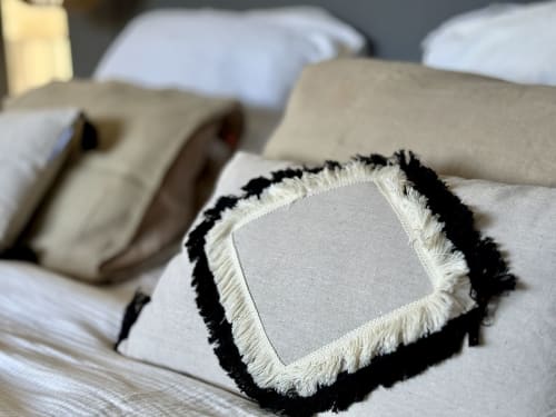 Oreiller décoratif à franges noires et crème sur la literie blanche de la VillaSerenita à Ajaccio, Corse, France