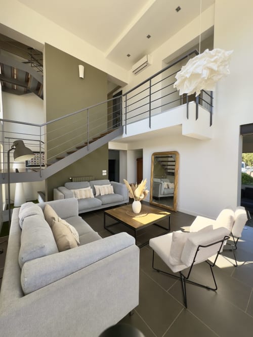 Spacieux séjour sur deux niveaux de la VillaSerenita à Ajaccio, Corse, France avec canapés gris, chaises blanches et mezzanine