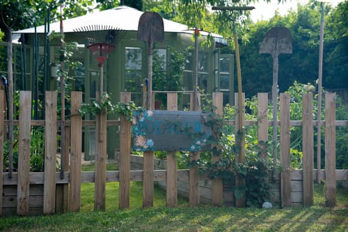 Maison Mûrier garden gate in Fayssac with wooden fence, green greenhouse, and decorative signage