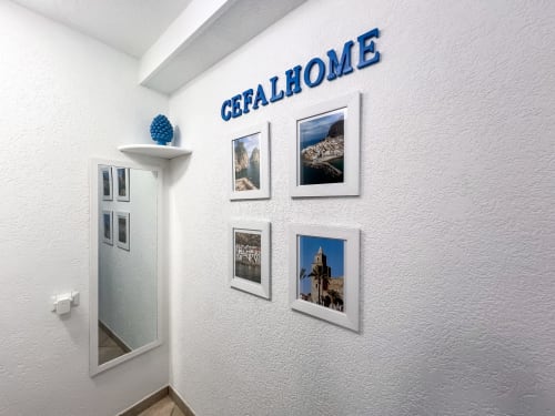 Entrée de CefalHome à Rome avec photos de paysages siciliens encadrées et éléments décoratifs bleus