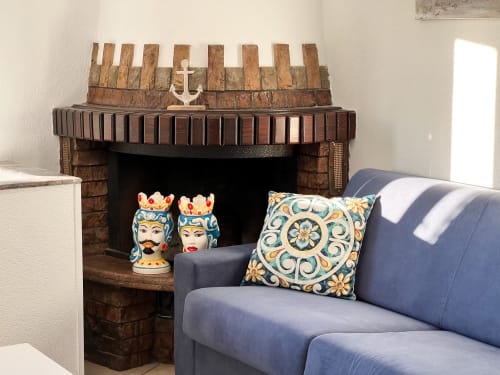 Canapé bleu avec coussin décoratif près de la cheminée en briques à l'hôtel CefalHome Roma