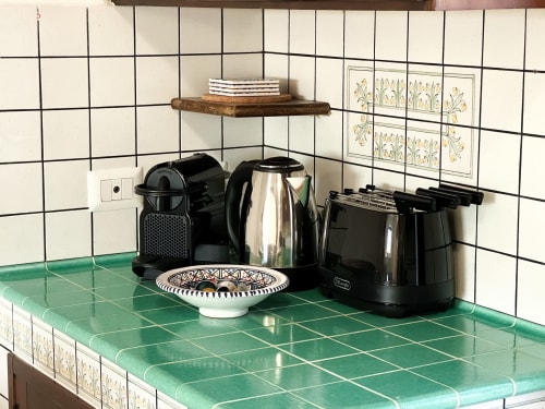 Coin cuisine CefalHome à Roma avec plan de travail en carrelage vert, cafetière, bouilloire et bol décoratif