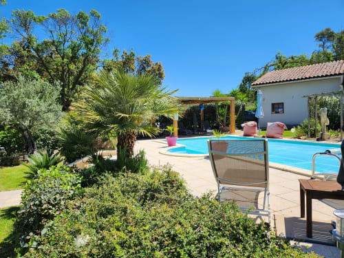 Poolbereich des Domaine à l'Aise BnB in Saint-Pargoire mit Liegestühlen, Palmen und weißem Cottage
