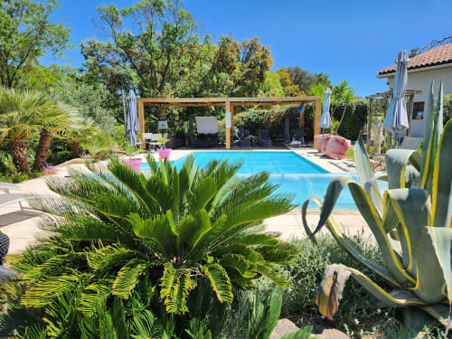 Espace piscine ensoleillé au Domaine à l'Aise à Saint-Pargoire avec pergola, transats et jardins méditerranéens luxuriants
