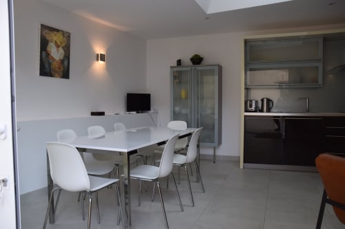 Espace repas contemporain du gîte Les Cordeliers au Fassardy, Châteauroux avec chaises blanches et accès à la cuisine