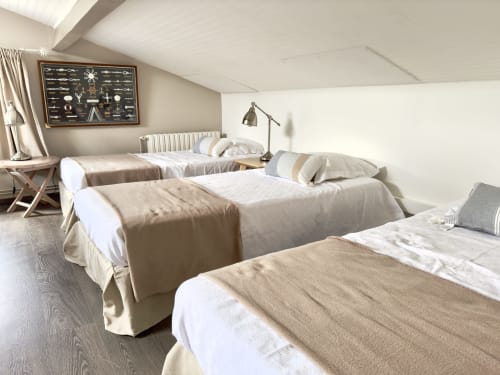 Chambre de la VillaSerenita Ajaccio avec trois lits, literie neutre et décoration nautique sous plafond mansardé