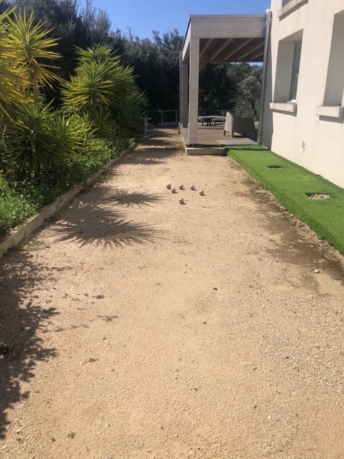 Terrain de pétanque de la VillaSerenita Ajaccio, avec palmiers et bâtiment de terrasse moderne